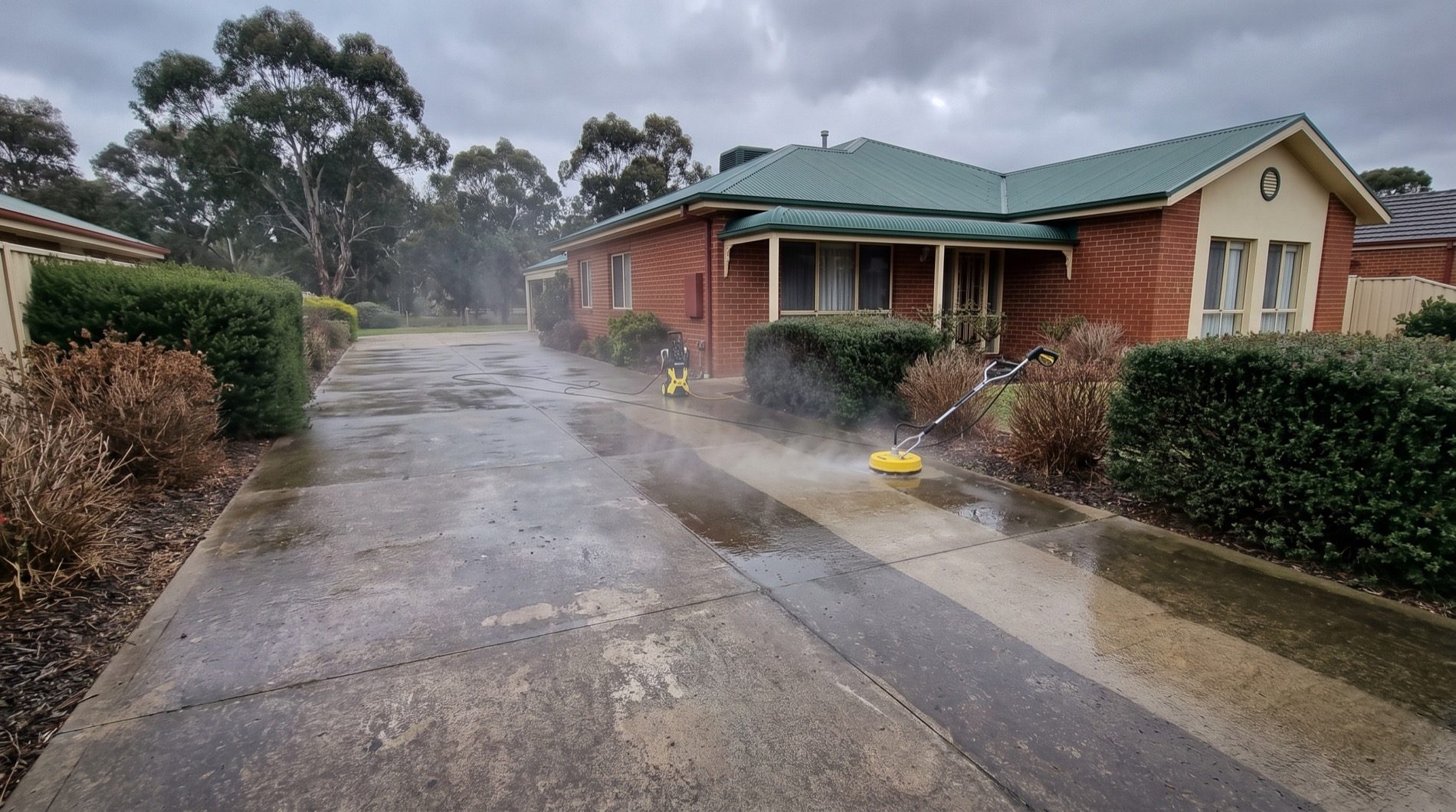 A driveway being pressure washed at a red brick Ballarat home under a grey sky