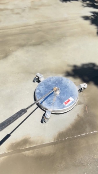 A surface cleaner spraying water across a concrete surface