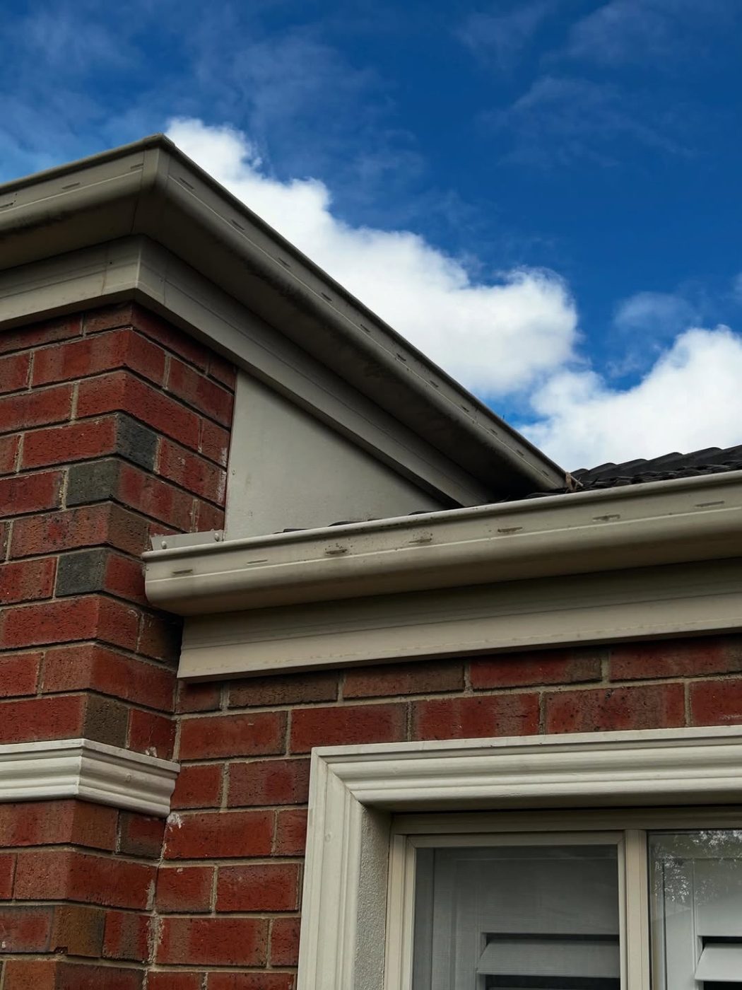 Gutters and eaves along the roofline of a red brick home